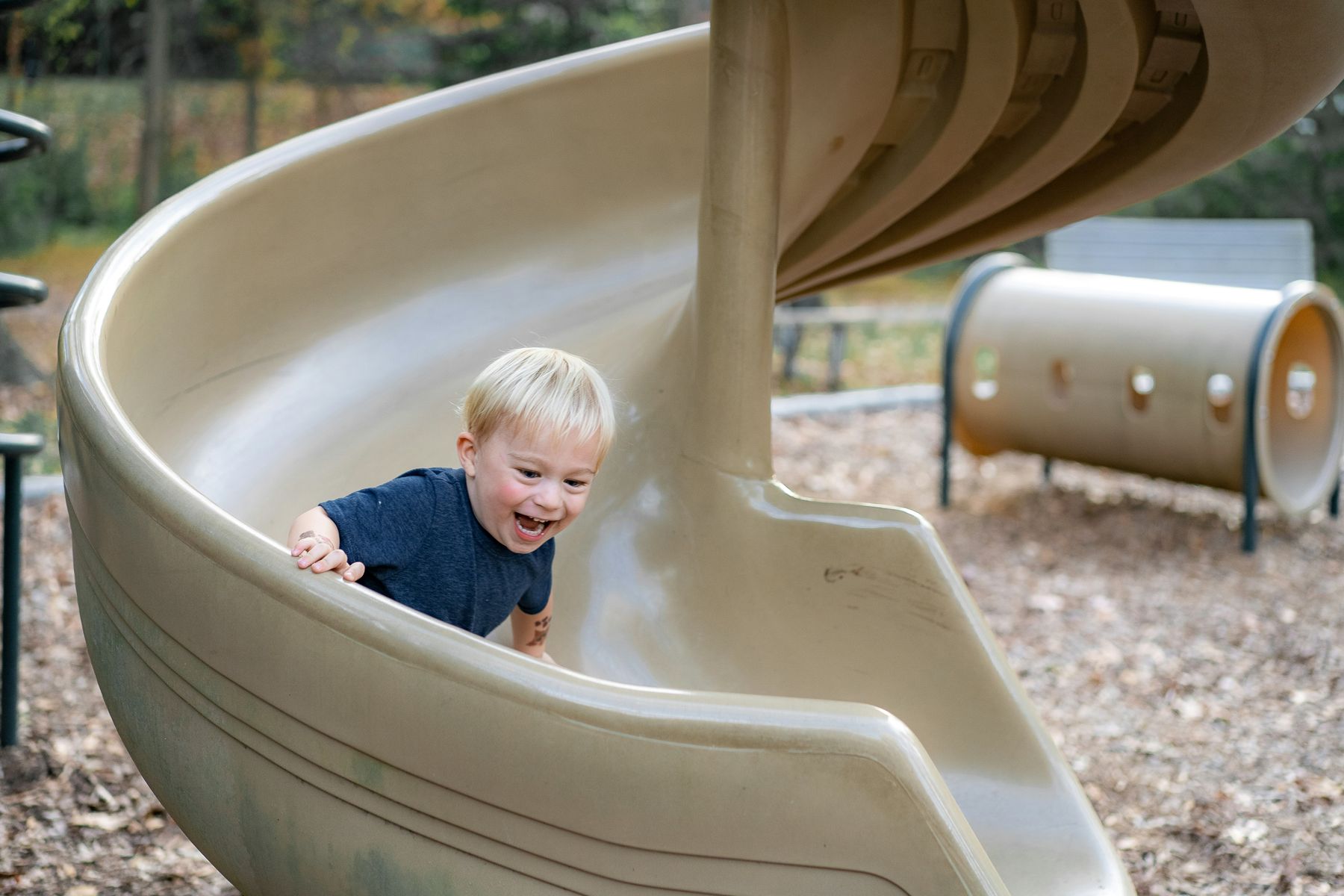 A toddler laughing on a spiral slide