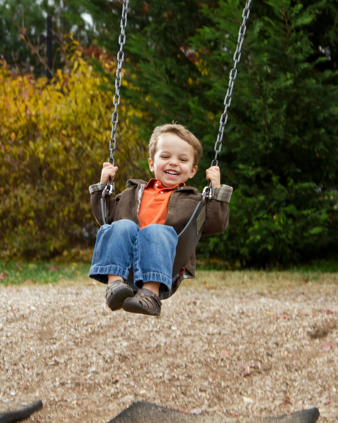 A laughing boy on a playground swing
